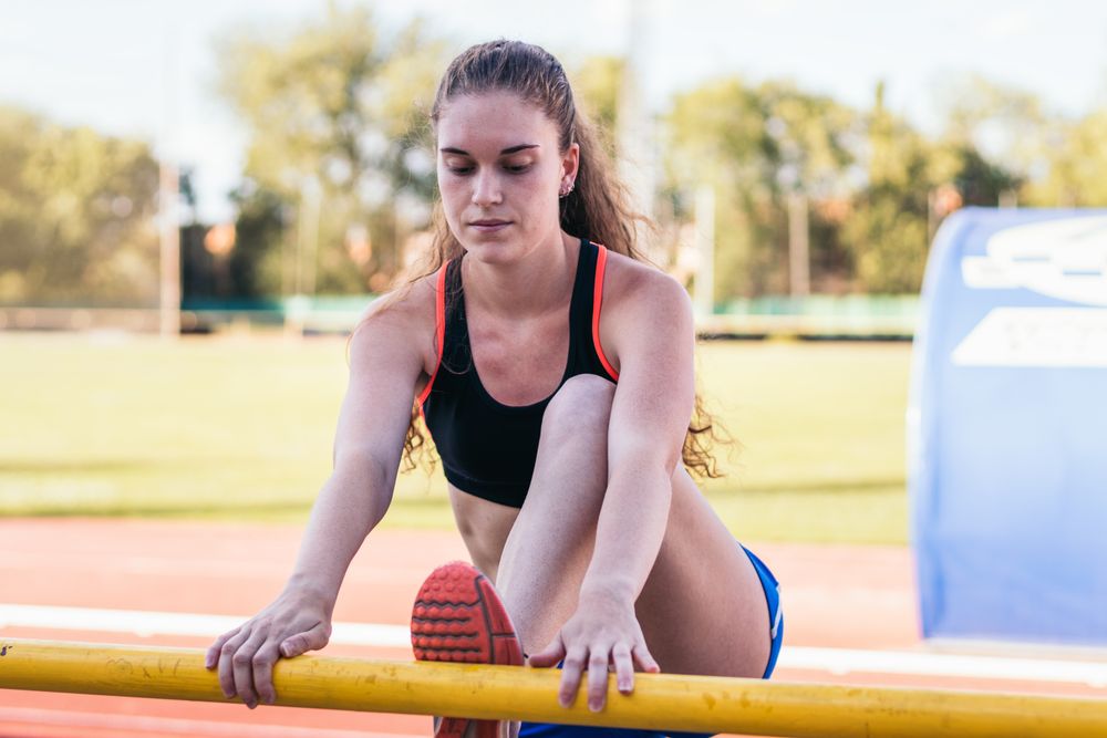 Female athlete stretching on an athletics track.