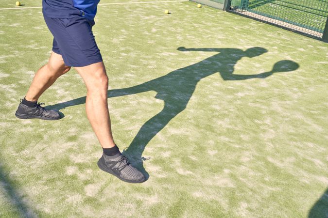Crop sportsman exercising on tennis court