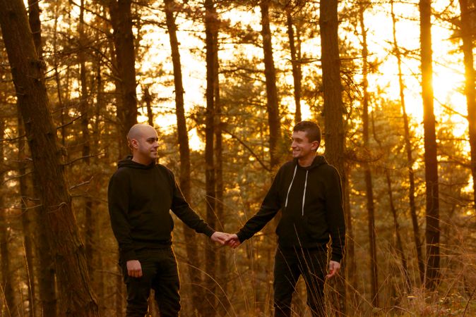 Men holding hands and walking in forest