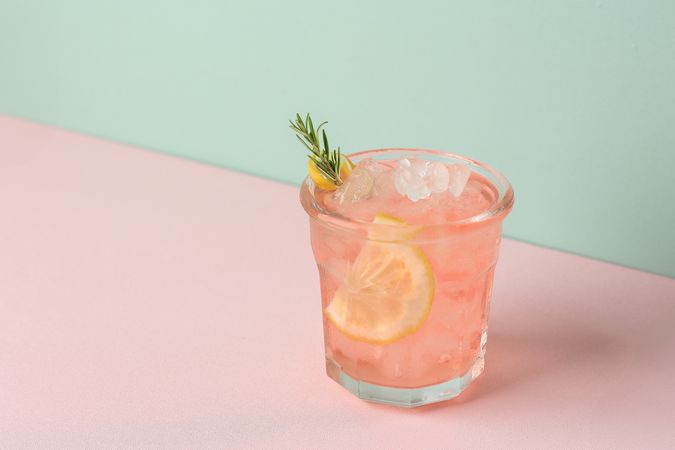 Refreshing Pink Drink or Cocktail with Ice, Garnished with a Slice of Lemon and Rosemary