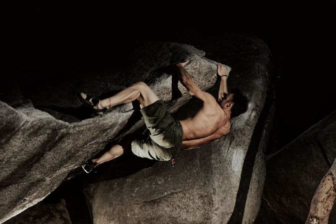 Man practicing rock climbing among large rocks in a forest