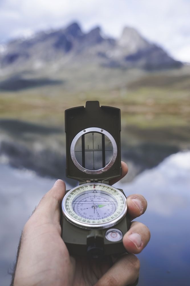 Crop hand with compass near lake