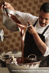 Man in apron pouring melted chocolate in kitchen 5lo8o0