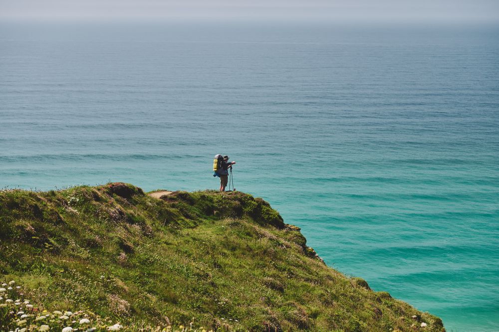Backpacker resting on top of cliff overlooking the sea