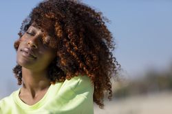 Content female with curly hair in bright green shirt with space for text