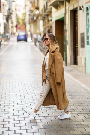 Woman in cream with brown coat crossing street