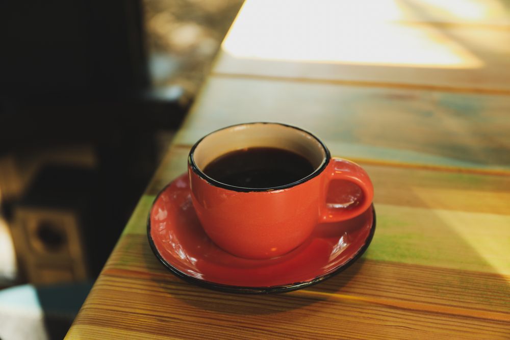 Cup of coffee on wooden table, space for text