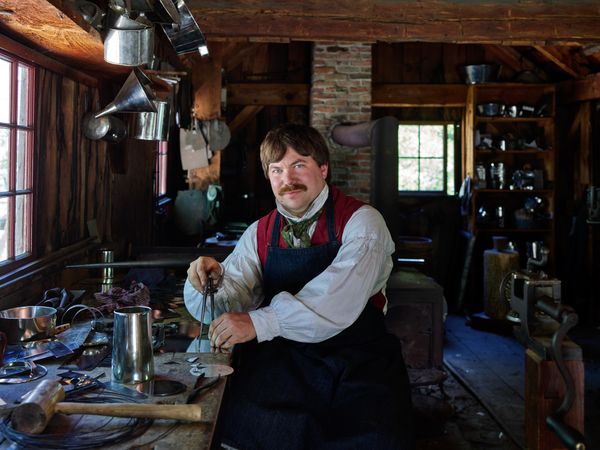 Costumed interpreter at work as a tinsmith at Old Sturbridge Village, Sturbridge, Massachusetts