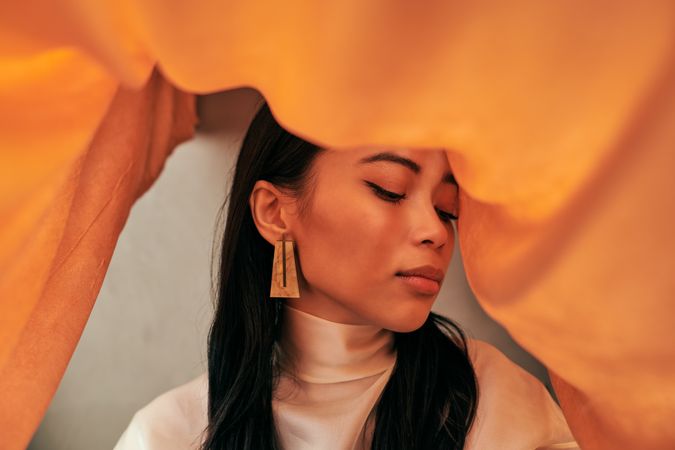Close up of young woman surrounded by orange fabric