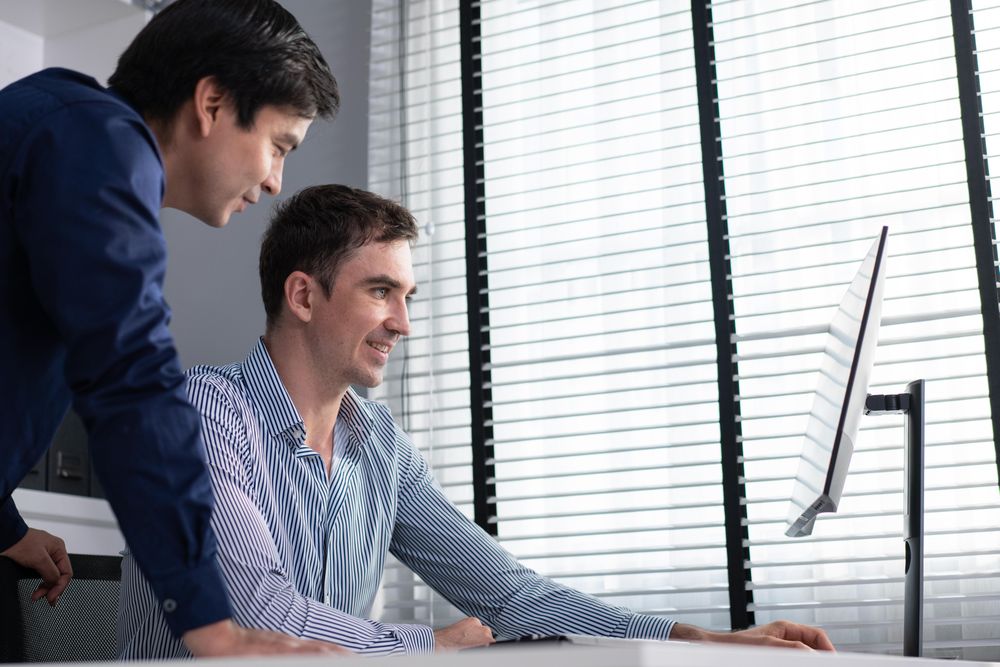 Colleagues talking together over screen in the office