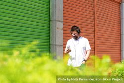 Man checking phone while walking next to colorful shutters 5rp2Pb
