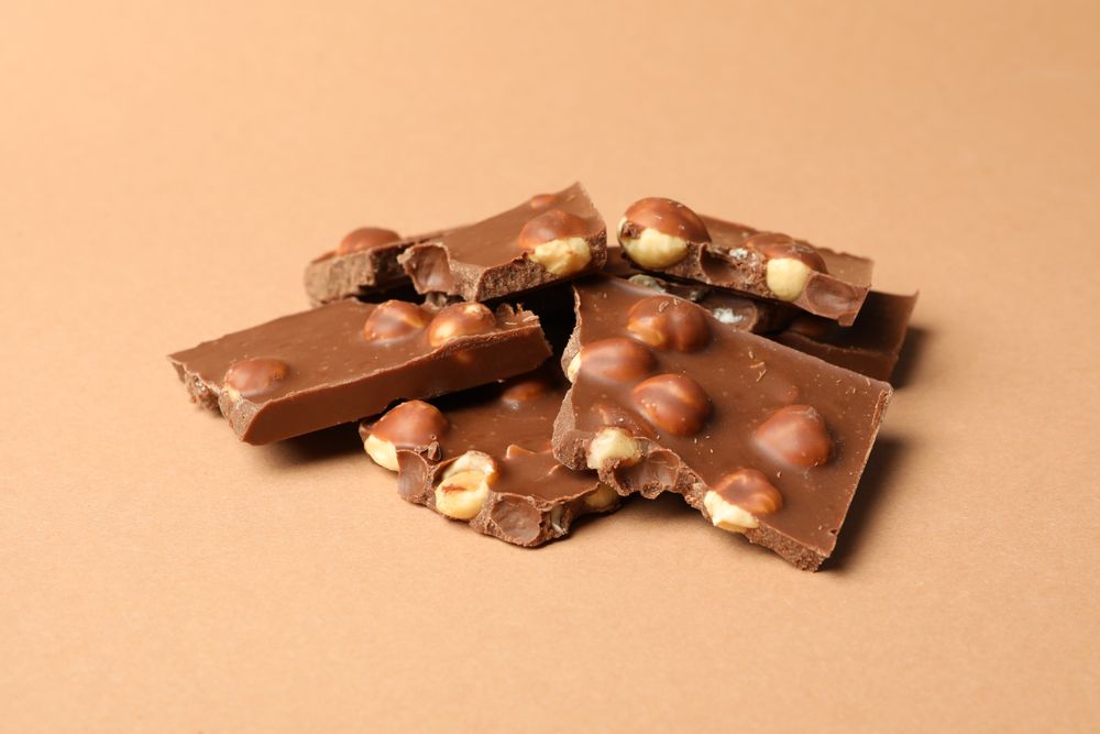 Chocolate pieces on beige background. Sweet food