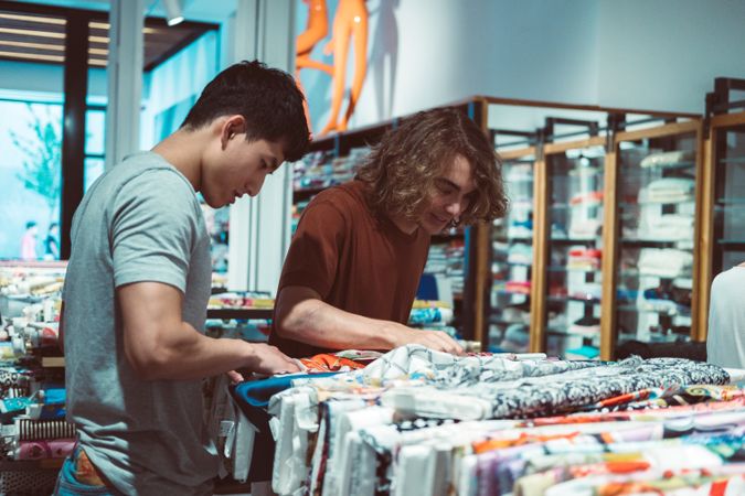 Captivated multiracial men looking for fabric in drapery store