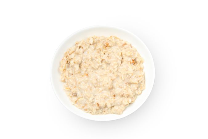 Plate with cooked oatmeal isolated on plain background