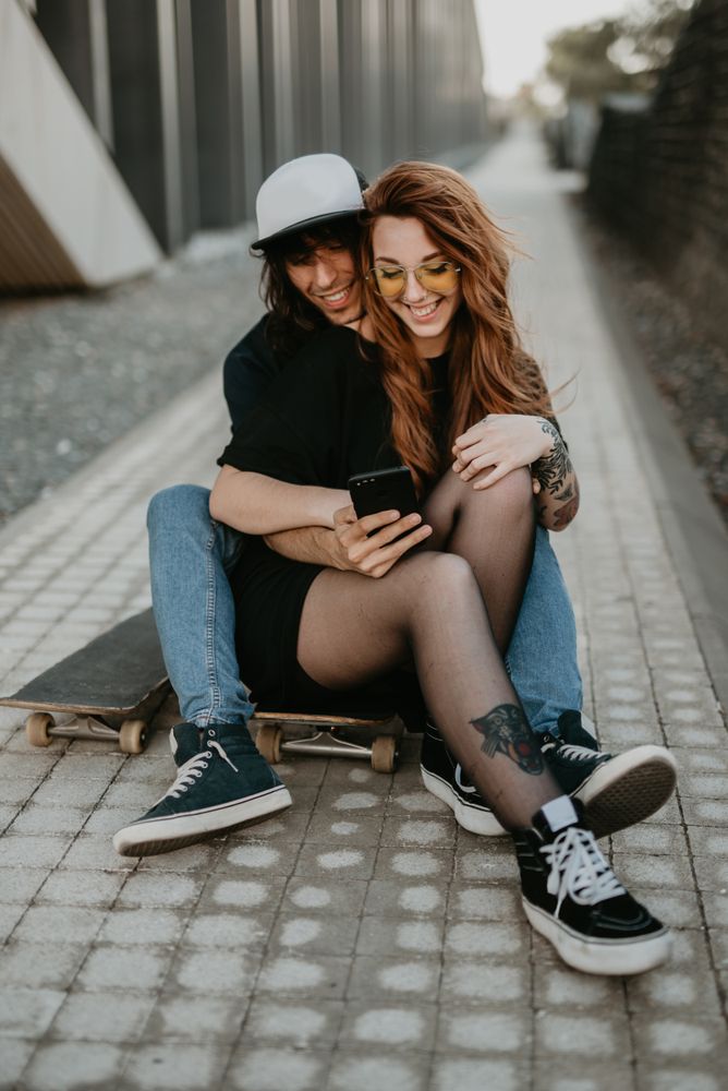 Skaters sitting on road on smartphone
