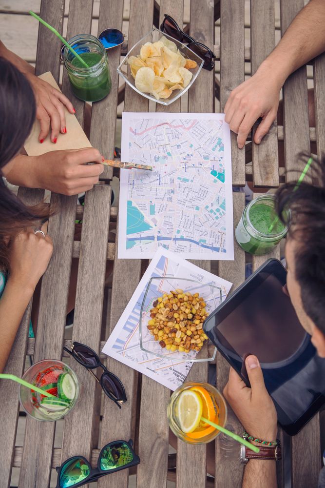 Hands of friends sitting on bench checking maps