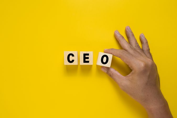 male hand put ceo symbol on wooden blocks. isolated on yellow background