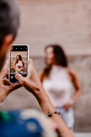 Faceless male taking photo of brunette woman