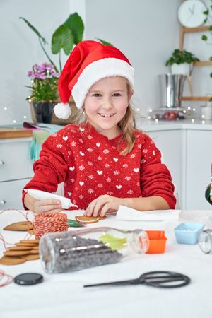 Content girl applying sweet icing on gingerbread cookie