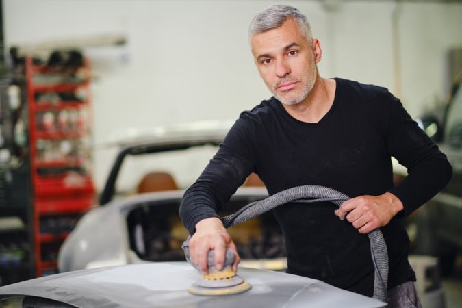 Mechanic grinding paint from car detail