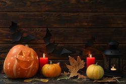 Halloween pumpkins and candles on dark wooden background, copy space