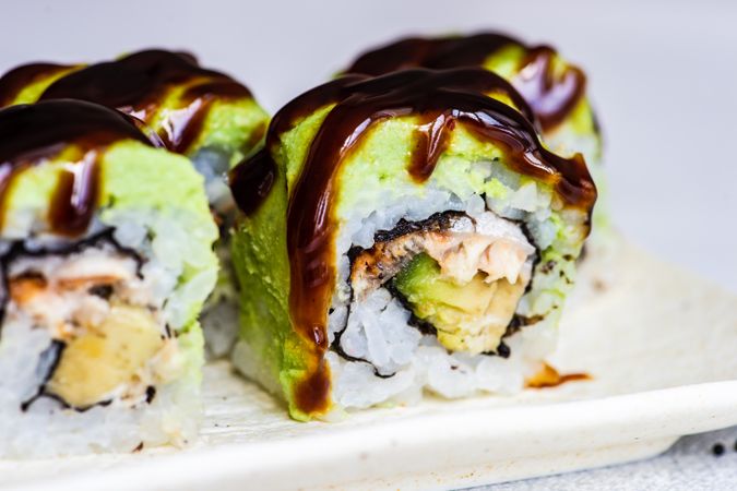 Close up of sushi rolls with avocado and eel sauce