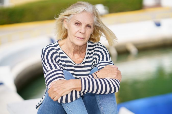 Portrait of older female relaxing on dock on sunny day