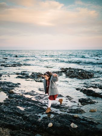 little girl walking on rocks at sea
