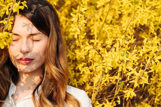 woman with closed eyes amidst yellow flowers