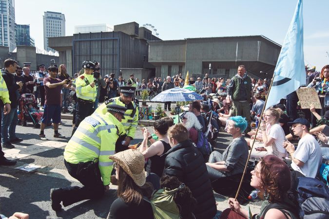 London, England, United Kingdom - April 19th, 2019: Police kneeling speaking to sitting protesters