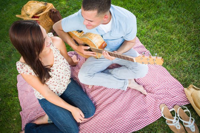 Young Male Playing Guitar for His Girlfriend in the Park.