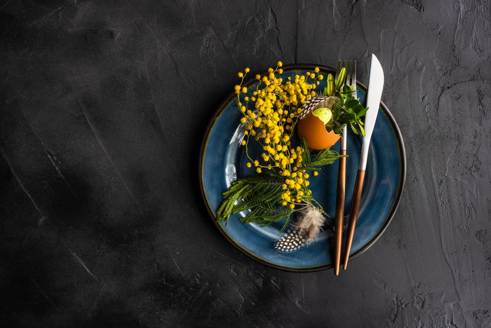 Top view of rustic table setting with decorate spring foliage on navy plate with copy space