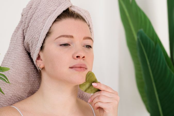 Woman performing facial massage with gua sha