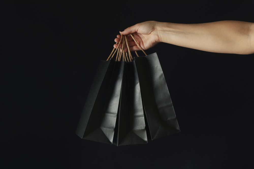 Female hand hold paper bags on dark background