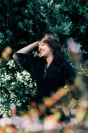 Smiling female looking out of green bushes