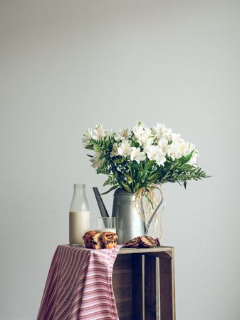 Milk and cupcakes near vase with flowers