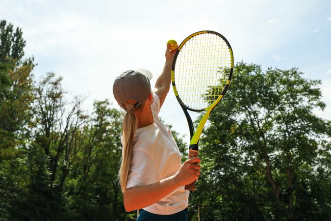 Young woman in white t-shirt serve the tennis ball
