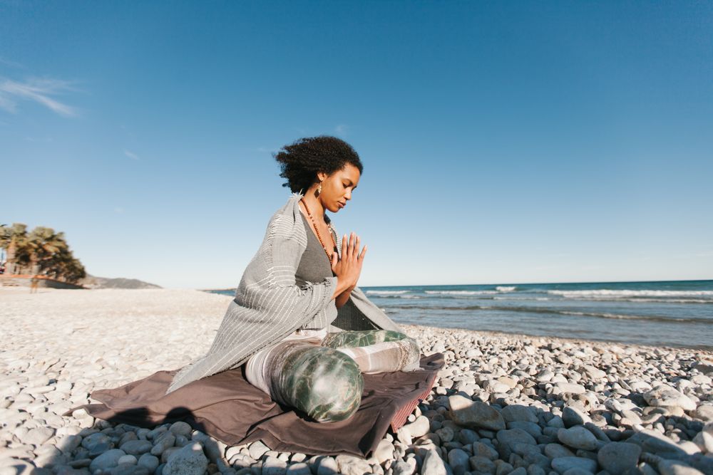 Sportive woman sitting on sandy beach in asana