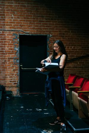 Female director standing with script in the front of the theater