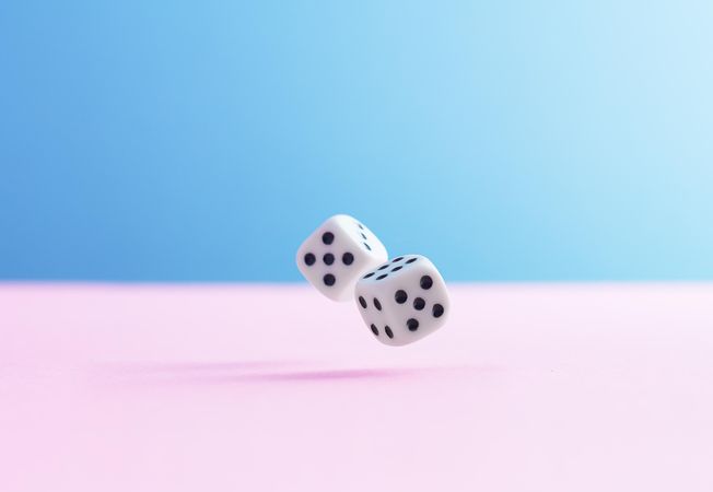 Two dice over pink and blue background