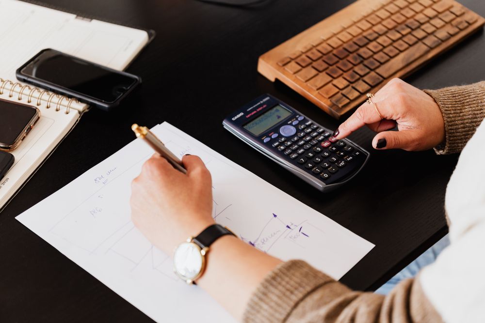 Woman using calculator and sitting at a desk