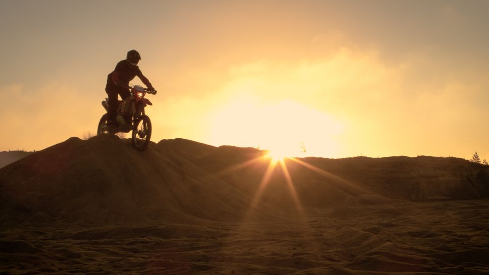Professional Motocross Motorcycle Rider Drives Over the Dune and Further Down the Off-Road Track.