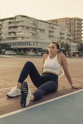 Athletic woman taking a break and resting on a basketball court after a workout in the city