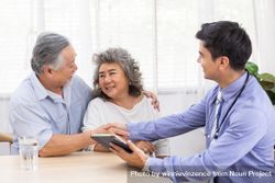 Doctor using digital tablet discussing prognosis with Asian patients 0Lwlgb