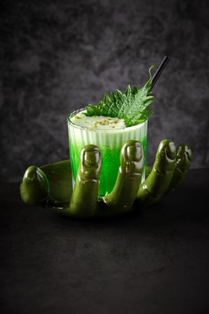 Green alcohol cocktail on serving plate in form of green hand