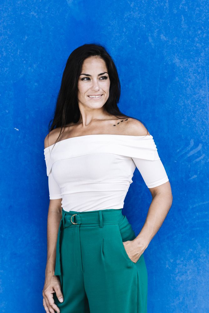Portrait confident smiling young woman against a blue wall
