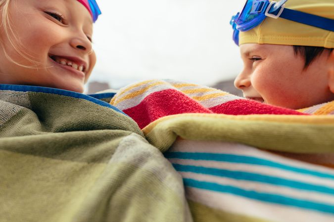 Close up of young boy and girl smiling and covered in towels