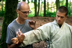 man training martial arts student in forest