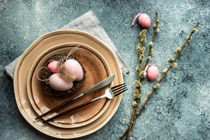 Top view of Easter holiday table setting with decorative pink Easter eggs & pussy willow
