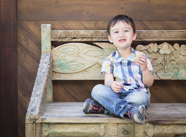 Cute Boy Sitting on Bench Eating Sandwich